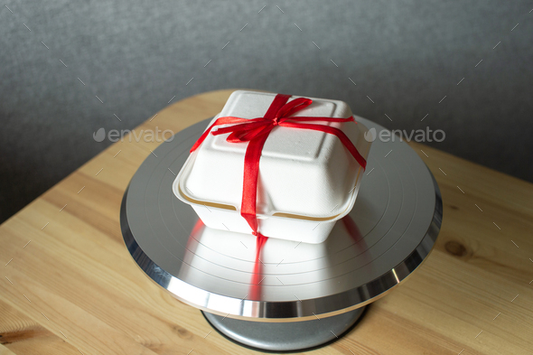 White box with red ribbon for cake bento on pastry metal turntable for cakes
