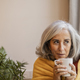 portrait of pretty mature woman with gray hair, sitting holding a mug with hot drink - PhotoDune Item for Sale