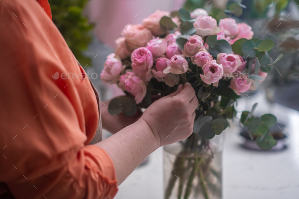 Professional floral artist carefully crafting a stunning pink rose arrangement.floral design studio