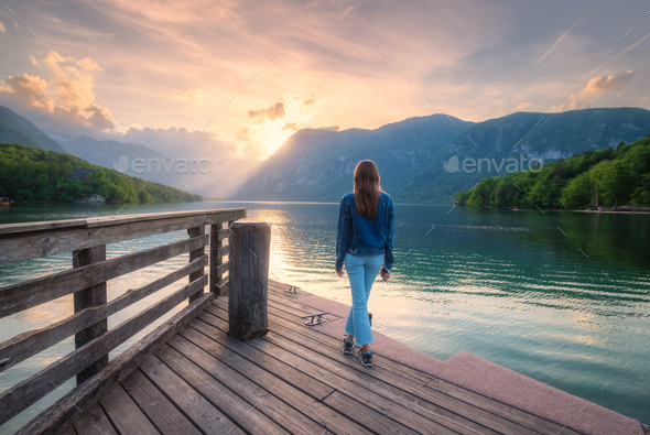 Woman and mountains reflected in lake at sunset in autumn - Stock Photo - Images