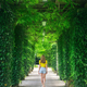Green trees alley and young woman in blooming park in summer - PhotoDune Item for Sale