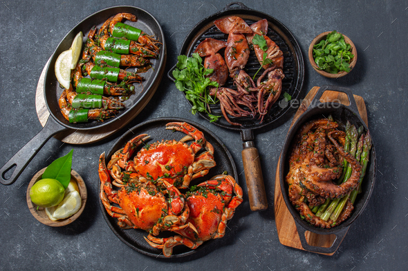Set of Seafood Dishes. Crabs, octopus, squids and tiger shrimps on cast iron pans and plates on a