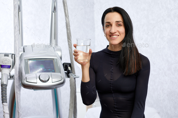 woman in a black suit for LPG massage drinking water before LPG massage. Anti-cellulite body care