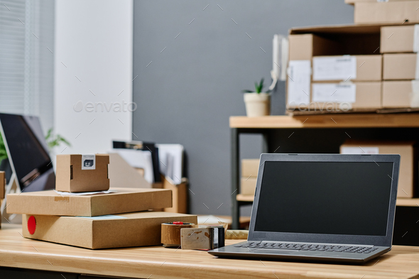 Laptop and stack of boxes on workplace of volunteer
