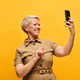 Cheerful blond woman in stylish beige dress looking at smartphone screen - PhotoDune Item for Sale