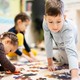 Children connecting jigsaw puzzle pieces in a kids room on floor at home.  - PhotoDune Item for Sale