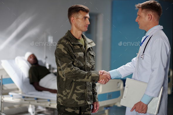 Soldier shaking hands with doctor in hospital - Stock Photo - Images