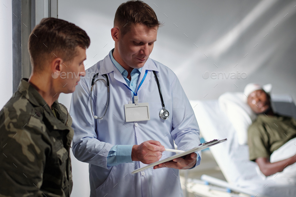 Doctor discussing diagnosis with soldier in hospital - Stock Photo - Images