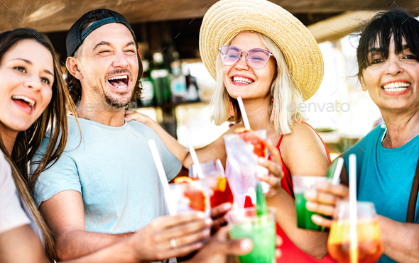 Mixed age range family friends toasting cocktails at chiringuito beach bar