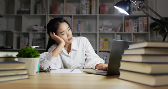 Woman working on laptop and sleeping on table. alt