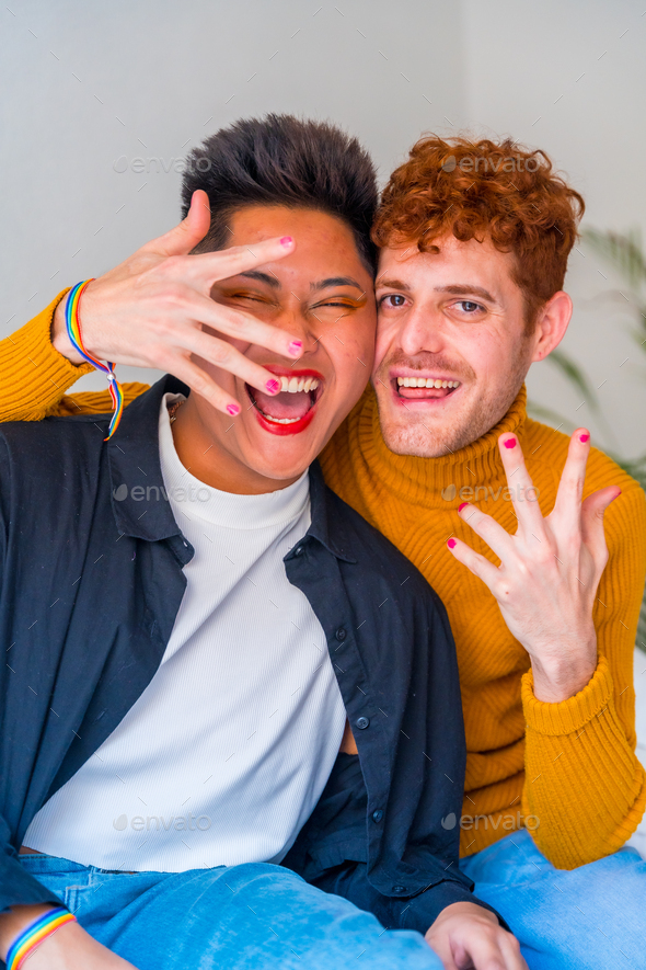 Portrait Of Beautiful Gay Couple Putting On Makeup With Painted Nails Indoors At Home Lgbt
