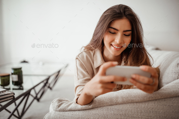 Glad happy millennial mixed race lady looking at phone, reading message, chatting in social networks