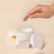 A woman hand using cream from Opened jar with a blank lid near orchid flowers, mockup - PhotoDune Item for Sale