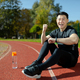 A young Asian man, an athlete sitting on a stadium treadmill. He looks at the smartwatch, fitness - PhotoDune Item for Sale
