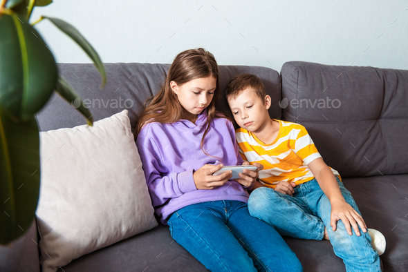 Two little toddler preschooler sibling gen Z kids using online parental control app on mobile phone