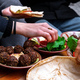 Close-up of female and male hands holding bread and spreading hummus.  - PhotoDune Item for Sale