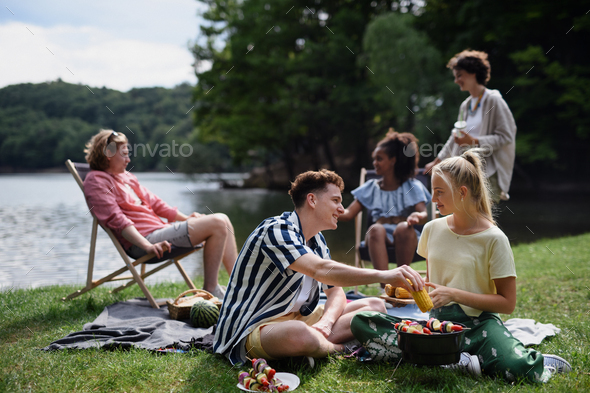 Group of multiracial young friends camping near lake and and having barbecue together. - Stock Photo - Images