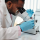 Side view of young African American male scientist looking in microscope - PhotoDune Item for Sale