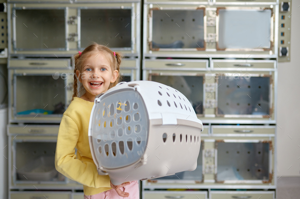 Portrait of little girl holding cage with new pet bought at veterinary shop - Stock Photo - Images