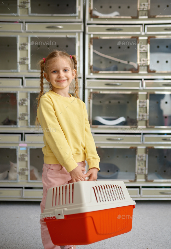 Portrait of little girl holding cage with new pet bought at veterinary shop - Stock Photo - Images