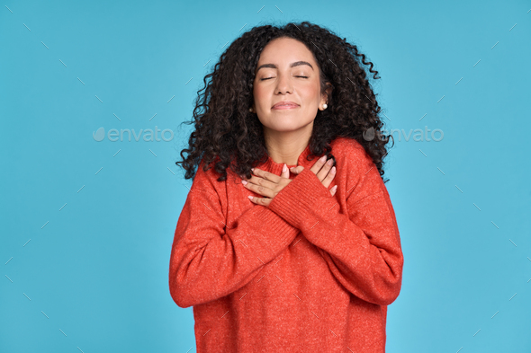 Happy latin woman holding hands on chest expressing gratitude isolated on blue. - Stock Photo - Images