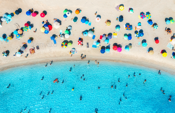 Aerial view of colorful umbrellas on beach, people in blue sea - Stock Photo - Images