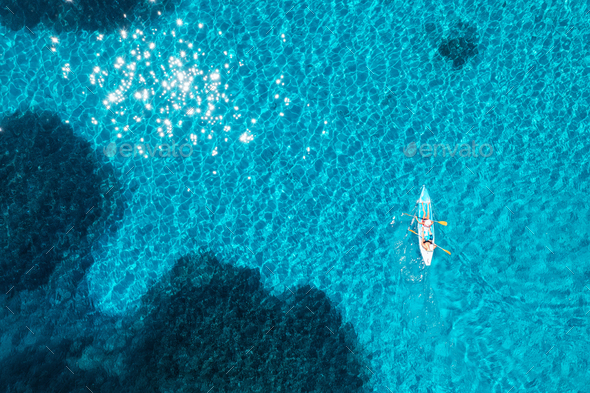 Aerial view of kayak with people in blue sea at sunset in summer - Stock Photo - Images