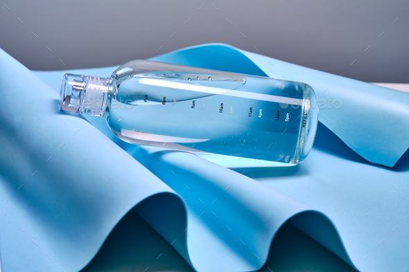A glass bottle of pure water against the background of blue waves. - Stock Photo - Images