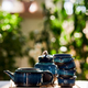 Tea set of deep blue color on a background of greenery. - PhotoDune Item for Sale