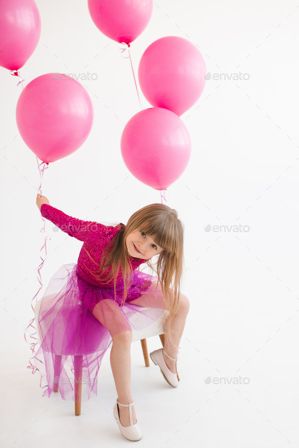 Funny kid girl celebrating birthday with balloons in room over white - Stock Photo - Images
