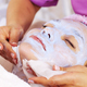 Cosmetologist removing  a mask scrub from female face. Woman in a spa salon on cosmetic procedures.  - PhotoDune Item for Sale