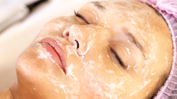 Cosmetologist applies  a moisturizing mask on female face. Woman in a spa salon, cosmetic procedures - Stock Photo - Images