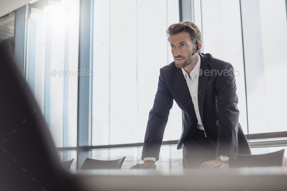 Portrait of businessman with bluetooth headset standing in conference room