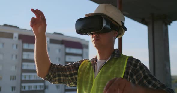 Engineer the Builder on the Roof of the Building Stands in VR Glasses and Moves His Hands Using the alt