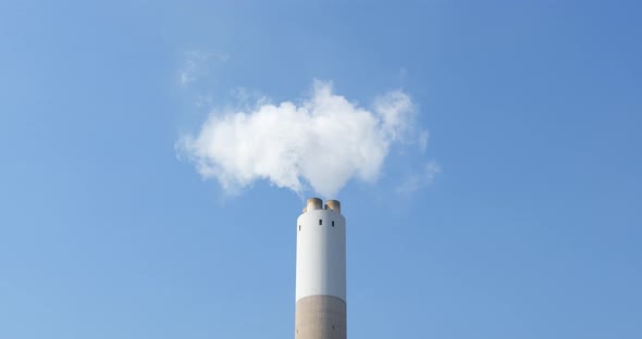 Chimney and smoke over blue sky  alt