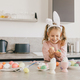 Happy cute little girl decorating Easter eggs using brush and paint on the kitchen. - PhotoDune Item for Sale