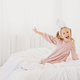 Cute happy little girl playing sitting on a bed with white linen near window. - PhotoDune Item for Sale