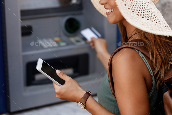 Close-up of woman using smart phone while withdrawing money from cash machine. - Stock Photo - Images