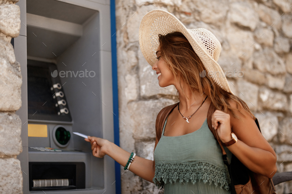 Happy woman using credit card while withdrawing money at ATM. - Stock Photo - Images