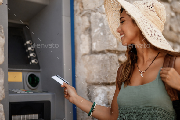 Smiling woman inserting credit card in ATM machine. - Stock Photo - Images
