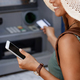 Close-up of woman using smart phone while withdrawing money from cash machine. - PhotoDune Item for Sale