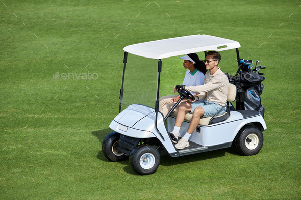 View at couple driving golf cart on green field minimal