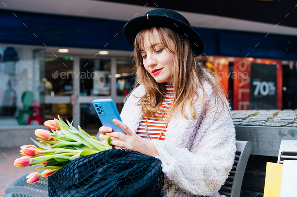 Stylish young woman using her phone for messaging, communication or content creating