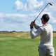 Back view of man playing golf and swinging golf club in sunlight at sports club - PhotoDune Item for Sale