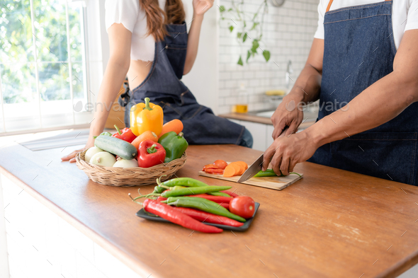 Happy Asian couple cooking together in kitchen at home. - Stock Photo - Images