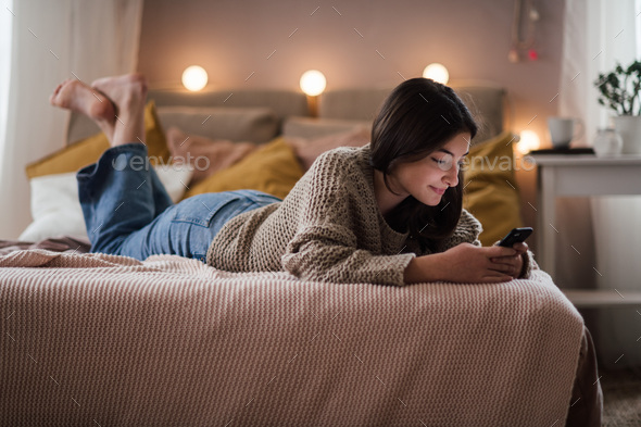 Young teenage girl srolling her smartphone in the room. - Stock Photo - Images