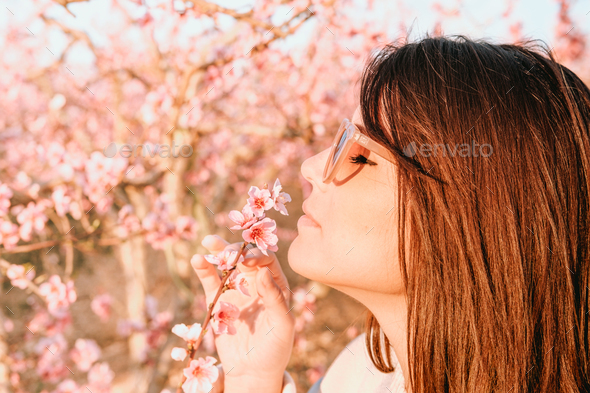 Young and beautiful woman deep breathing the fragrance of a cherry blossom flower