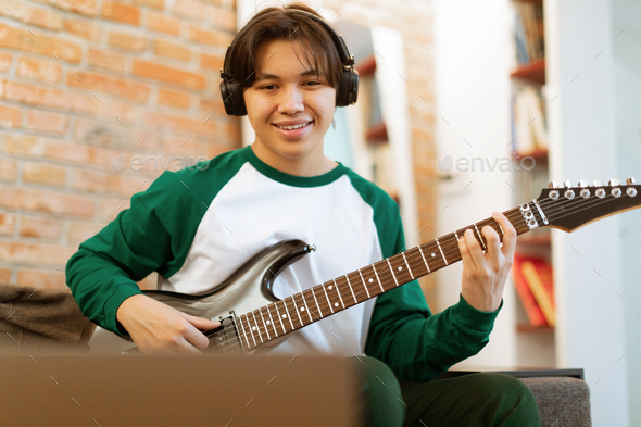 Korean Boy Playing Electric Guitar Near Laptop Sitting At Home - Stock Photo - Images
