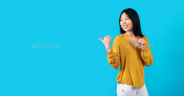 Cute young korean woman in casual pointing at copy space - Stock Photo - Images