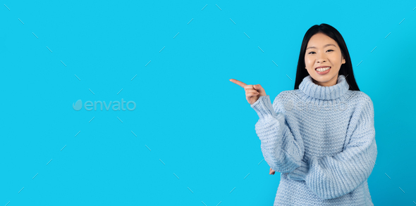 Cheerful pretty korean woman showing empty space for ad - Stock Photo - Images